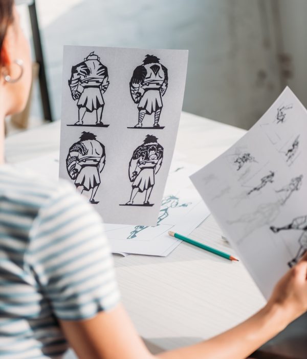 selective focus of illustrator holding papers with sketches